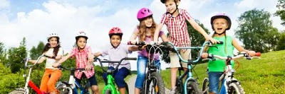 Kids smiling on bicycles wearing their helmets properly. 