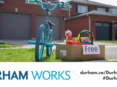  picture of a bike and a box of items marked as free on the curb of a residential home, with the Durham Works logo and text reading durham.ca/DurhamWorks #DurhamWorks 