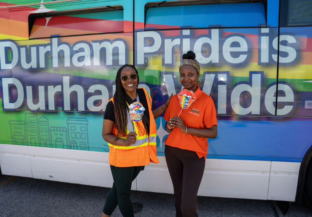 DRT ambassadors stand in front of the pride-wrapped DRT bus.