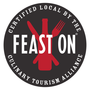 Feast On Logo which is a circle with the words "Feast On" over top an outline of a fork, knife, and bottle.