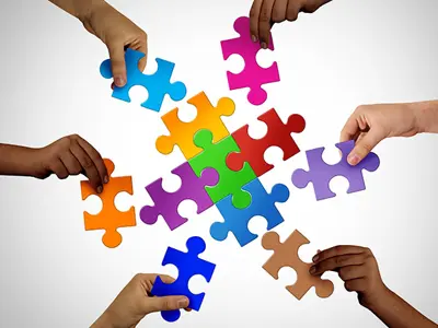 Hands holding coloured puzzle pieces