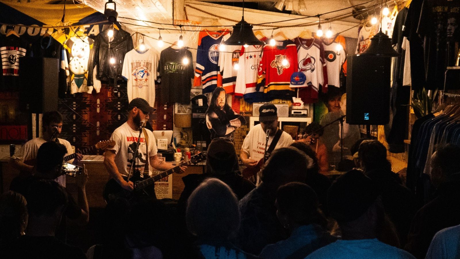 Band performing to a crowd in front of merch