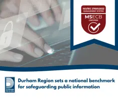 Promotional graphic showing a close-up of hands typing on a keyboard with a digital lock icon overlay, symbolizing cybersecurity. On the right side, a red badge reads “ISO/IEC 27001:2022 Management System – MS ECB Certified” with a checkmark. At the bottom, Durham Region branding appears alongside the text: “Durham Region sets a national benchmark for safeguarding public information.” 