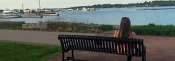 Woman sitting on a bench overlooking the Port Perry waterfront