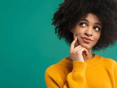 Person in a yellow sweater looking thoughtful against a teal background.