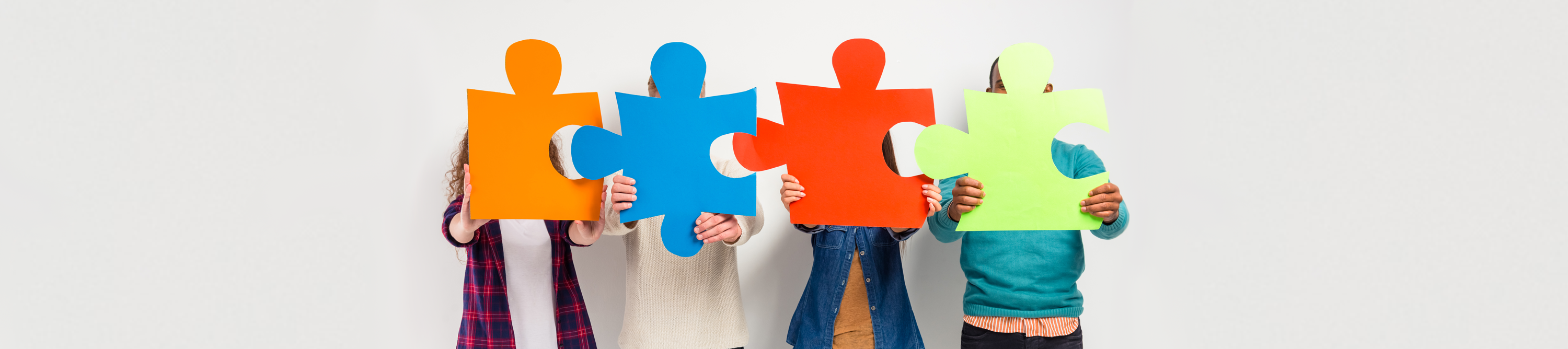 Youth holding puzzle pieces in front of their faces
