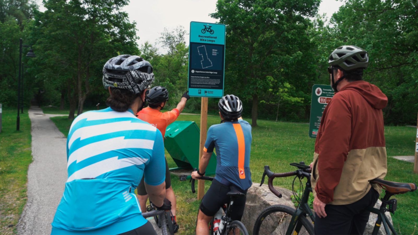 Recreational cyclists looking at cycling loop signage on trail