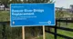 A sign announcing the Beaver River Bridge Replacement, with the temporary Beaver River Bridge in the background.