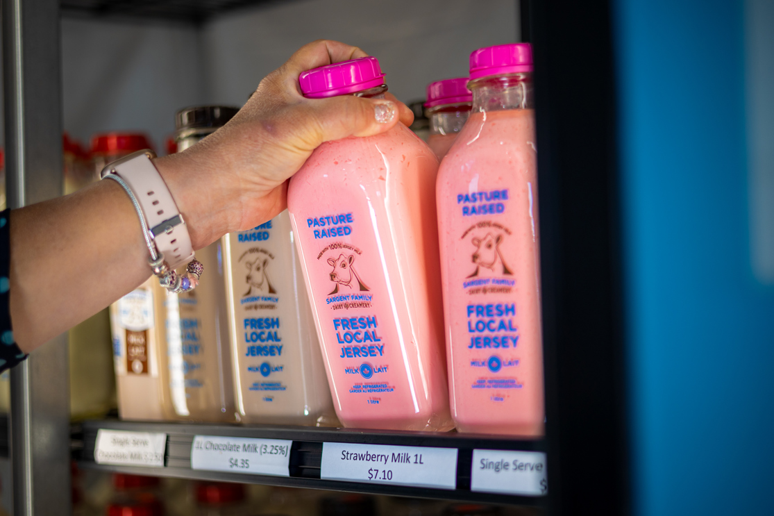 Grabbing a bottle of local strawberry milk from a fridge.