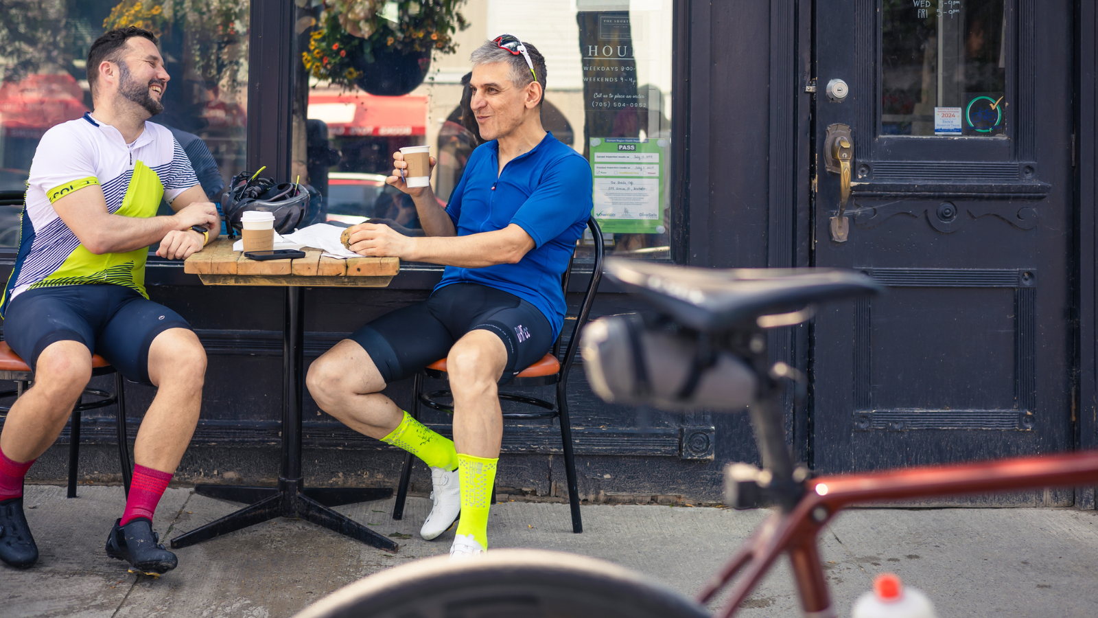Two cyclists at a cafe table having coffee