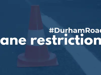 A pylon on a road, with a dark blue filter over top and white text that reads #DurhamRoads Lane restrictions