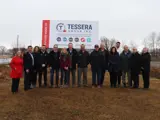 A group of people posing at a construction site for a new business announcement with a Tessera Group sign behind them.