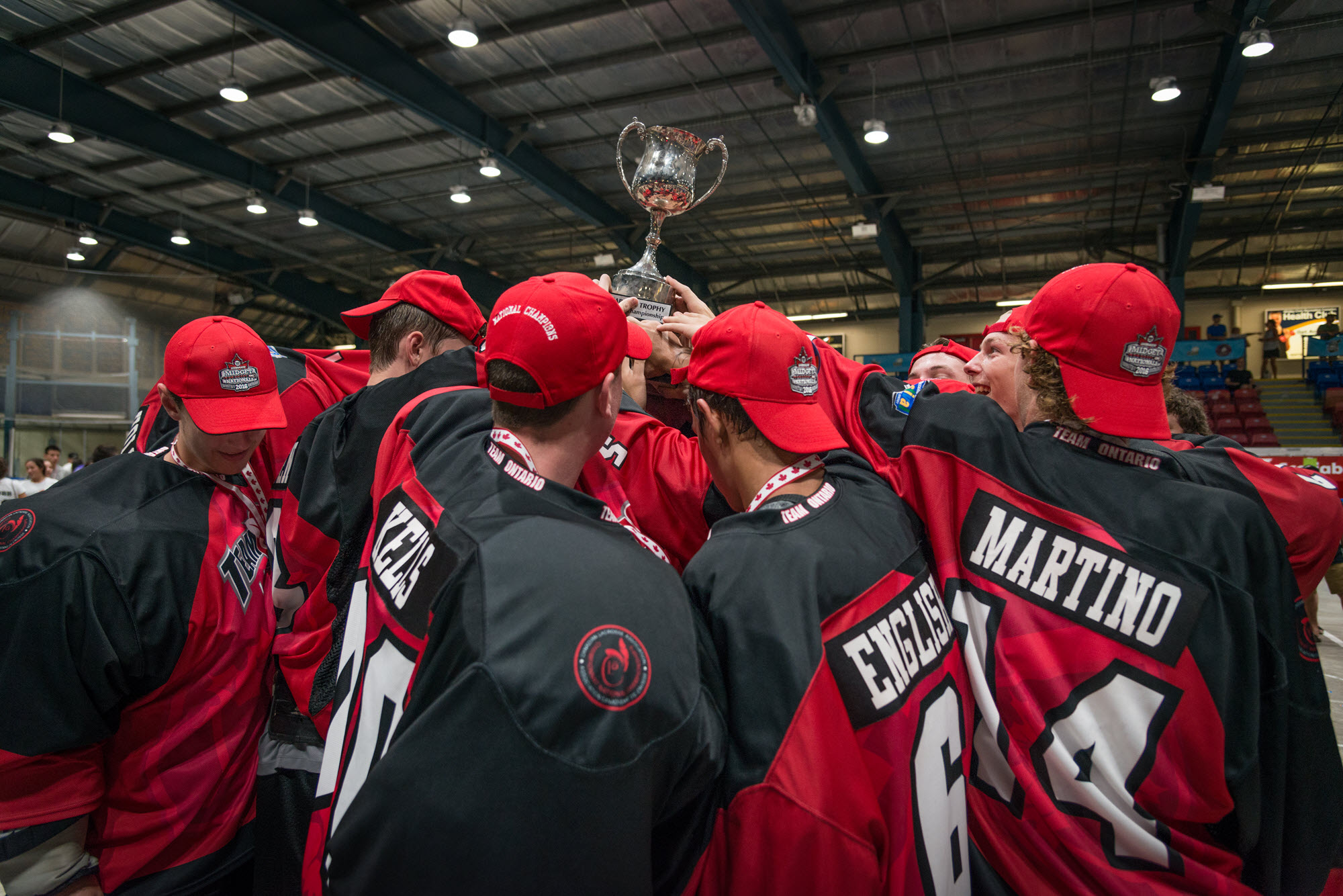 Sports team in black and red jerseys holding a championship trophy