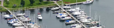 Aerial view of a marina with boats docked along piers near shoreline and park