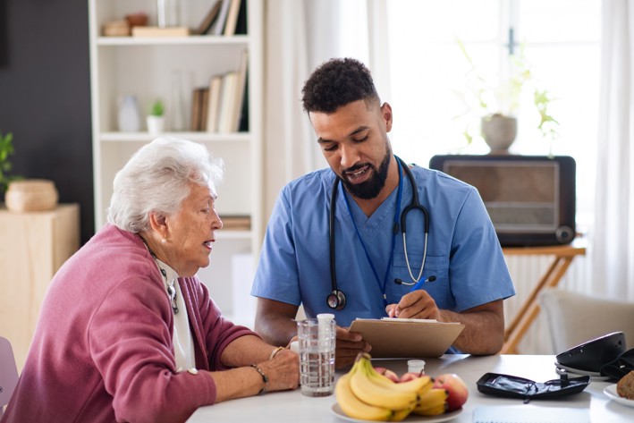 Healthcare worker reviewing notes with a senior at a table