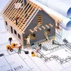 A construction team working to build a home on top of a blueprint drawing