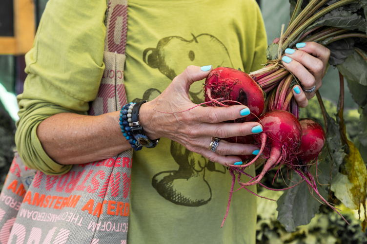 Beets in a shopper's hands at a farmers' market.