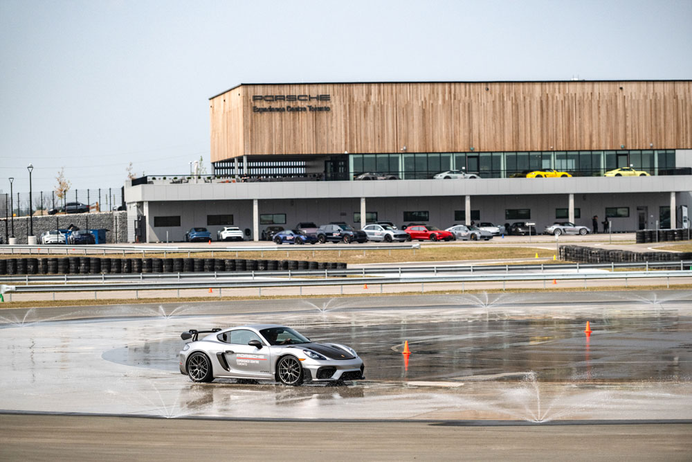 Porsche driving on Experience Centre Track with building in background.